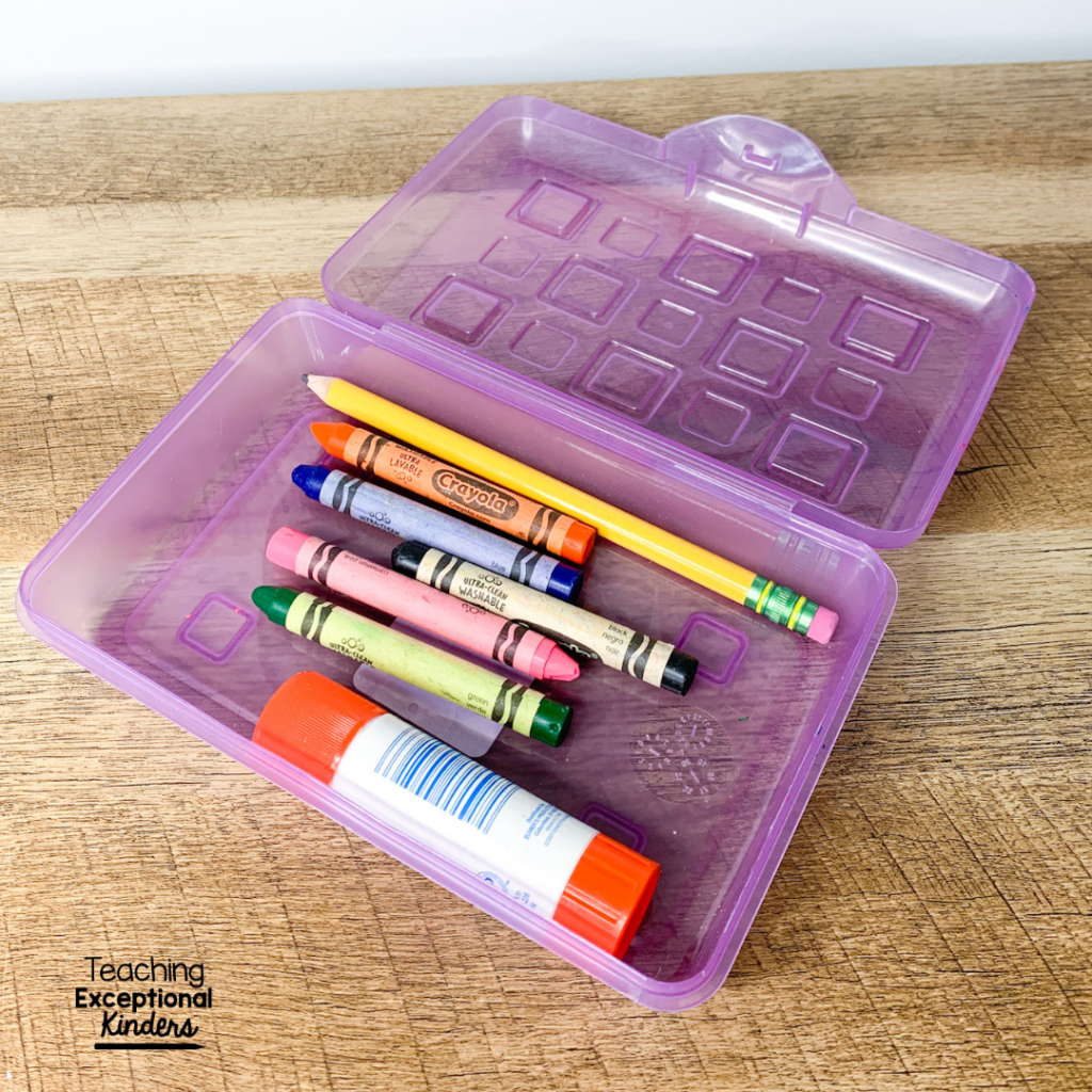 A pencil box with crayons, pencil and glue stick