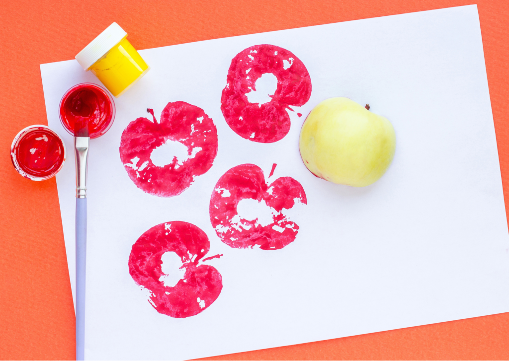 Stamping apples with red paint onto white paper