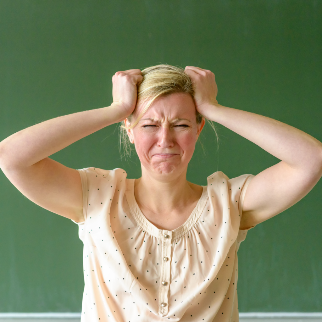 A teacher holding her hands to her head in frustration